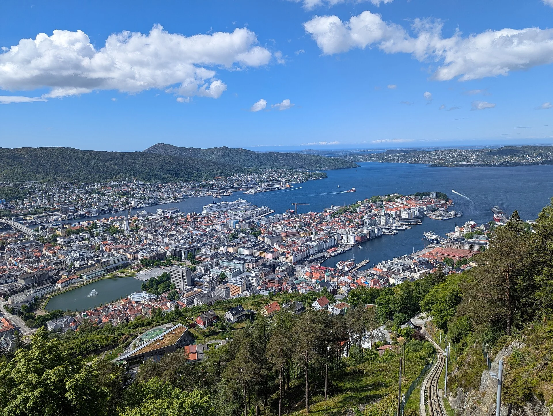 Blick vom Fløyen über Bergen mit Hafen, Fjord und den Schienen der Fløibanen im Vordergrund.