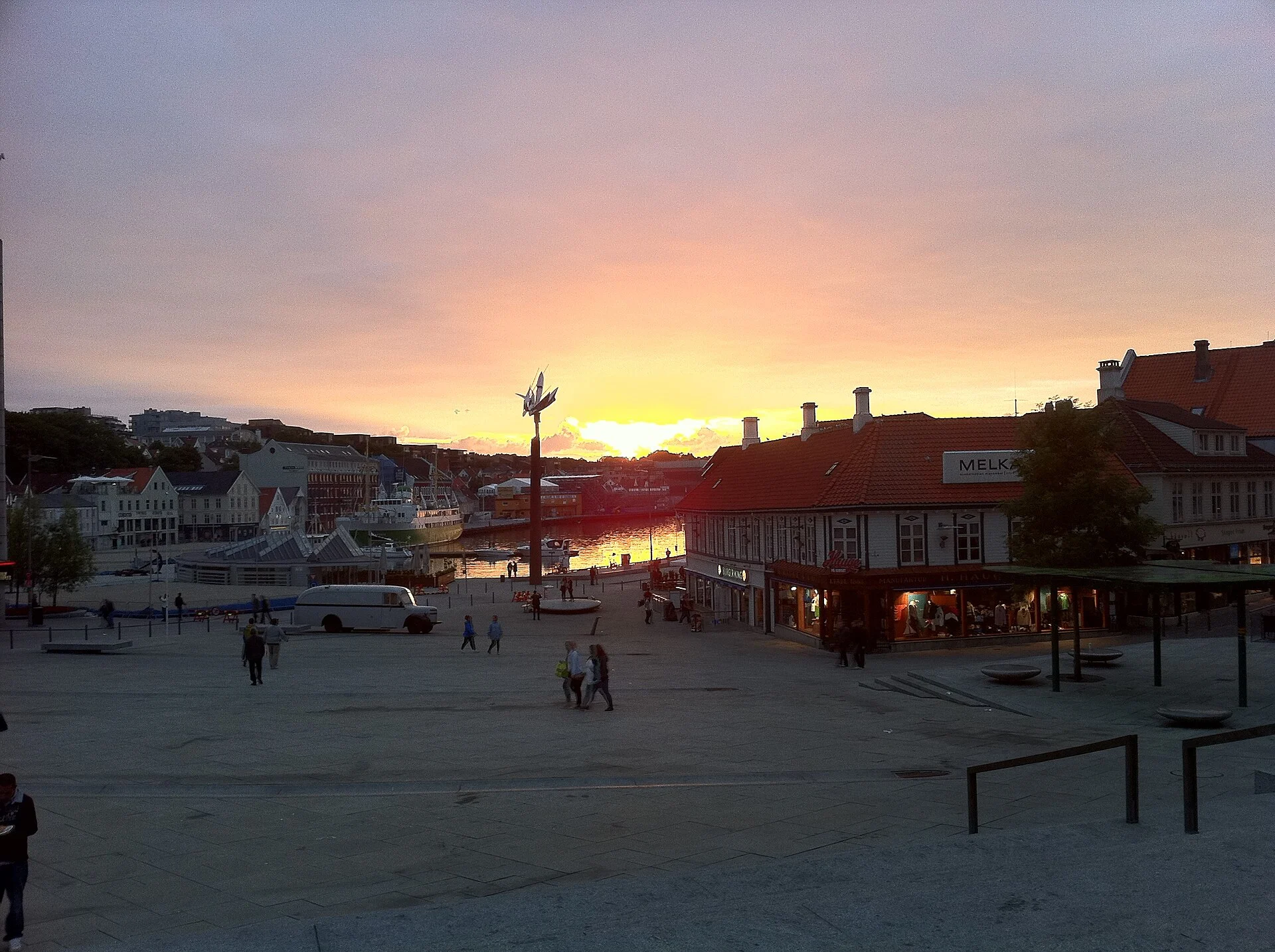 Blick über den Torget auf den innerstädtischen Hafen von Stavanger mit alten Holzhäusern bei Sonnenuntergang.