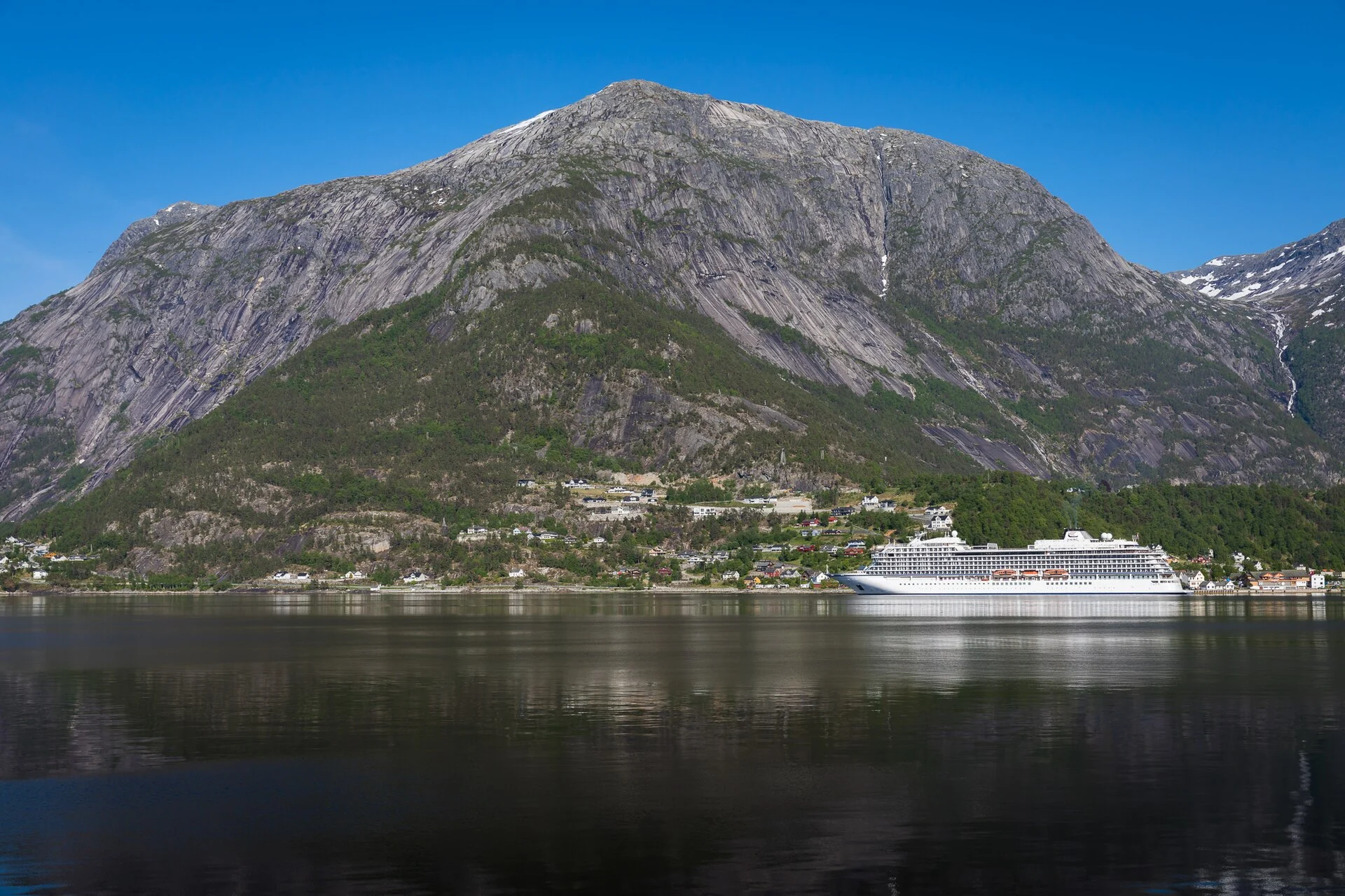 Der Ort Eidfjord am Hardangerfjord mit anliegendem Kreuzfahrtschiff unter der steilen Bergwand.