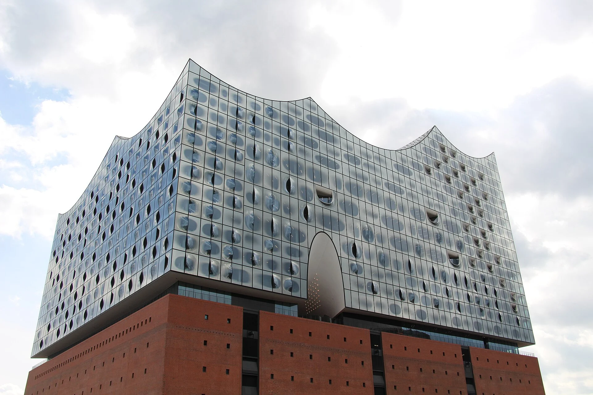 Frontale Ansicht der Elbphilharmonie in Hamburg mit dem Eingangsbogen zur Plaza über dem Backsteinsockel.